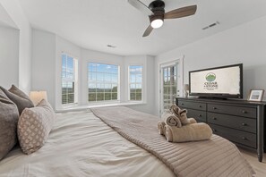 A bedroom with a bed, a television, a dresser, and a ceiling fan. - Gated Lake View Condo W/ pool, private boat ramp, putt putt, views of lake (Kimberling City)