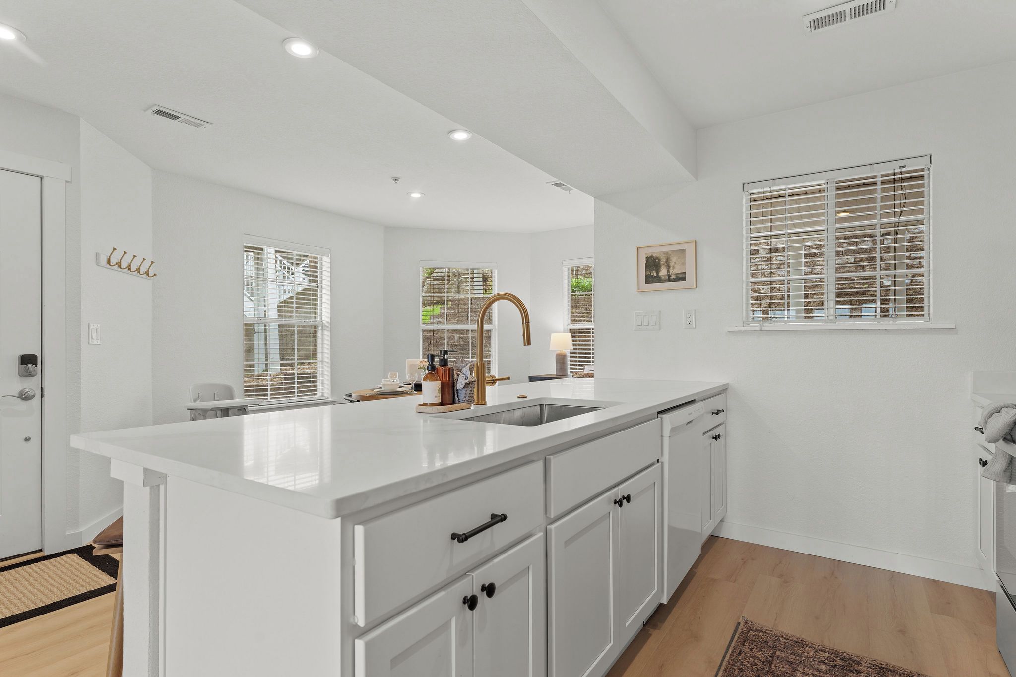 A modern kitchen with white cabinetry, a large island, and a stainless steel sink.