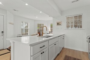 A modern kitchen with white cabinetry, a large island, and a stainless steel sink.
