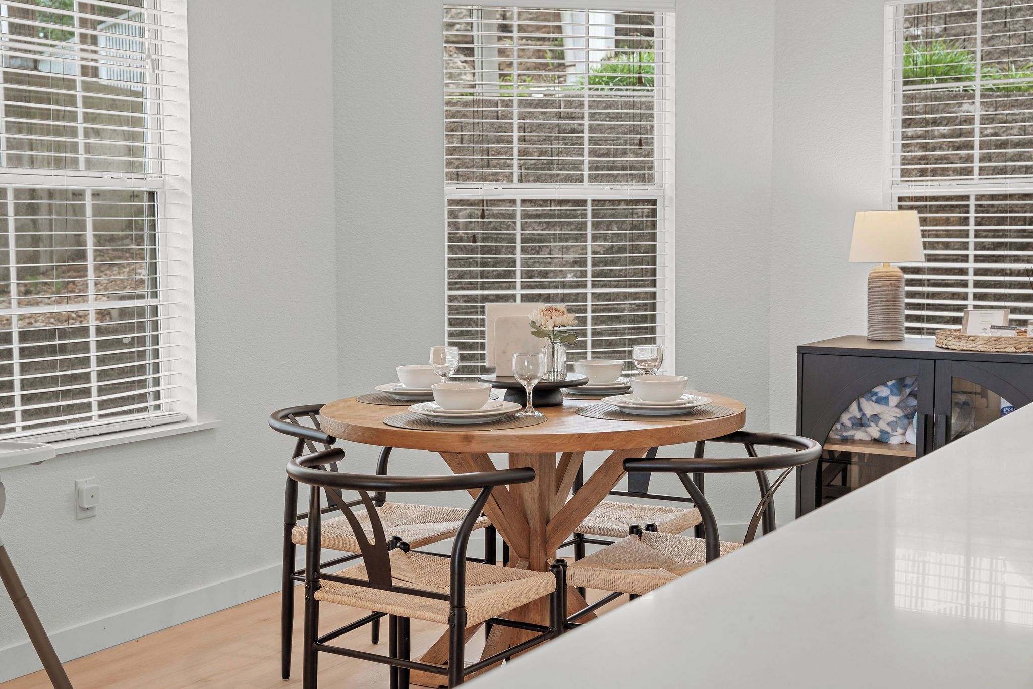 A dining area with a round table, chairs, and a window with blinds.