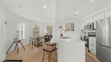 A modern kitchen with white cabinetry, stainless steel appliances, and a central island.