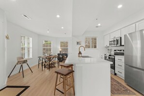 A modern kitchen with white cabinetry, stainless steel appliances, and a central island. - Gated Lake View Condo W/ pool, private boat ramp, putt putt, views of lake (Kimberling City)