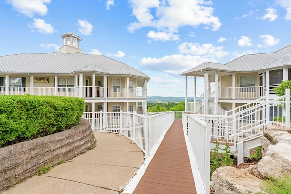 A coastal hotel with a wooden deck leading to a white fence and a view of the ocean.