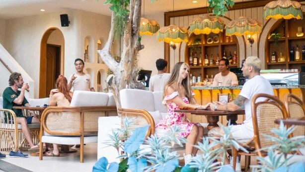 Un restaurante con terraza, zona de bar y un árbol que da sombra.