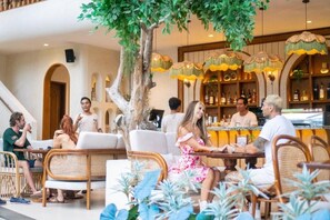 Un restaurante con terraza, zona de bar y un árbol que da sombra.