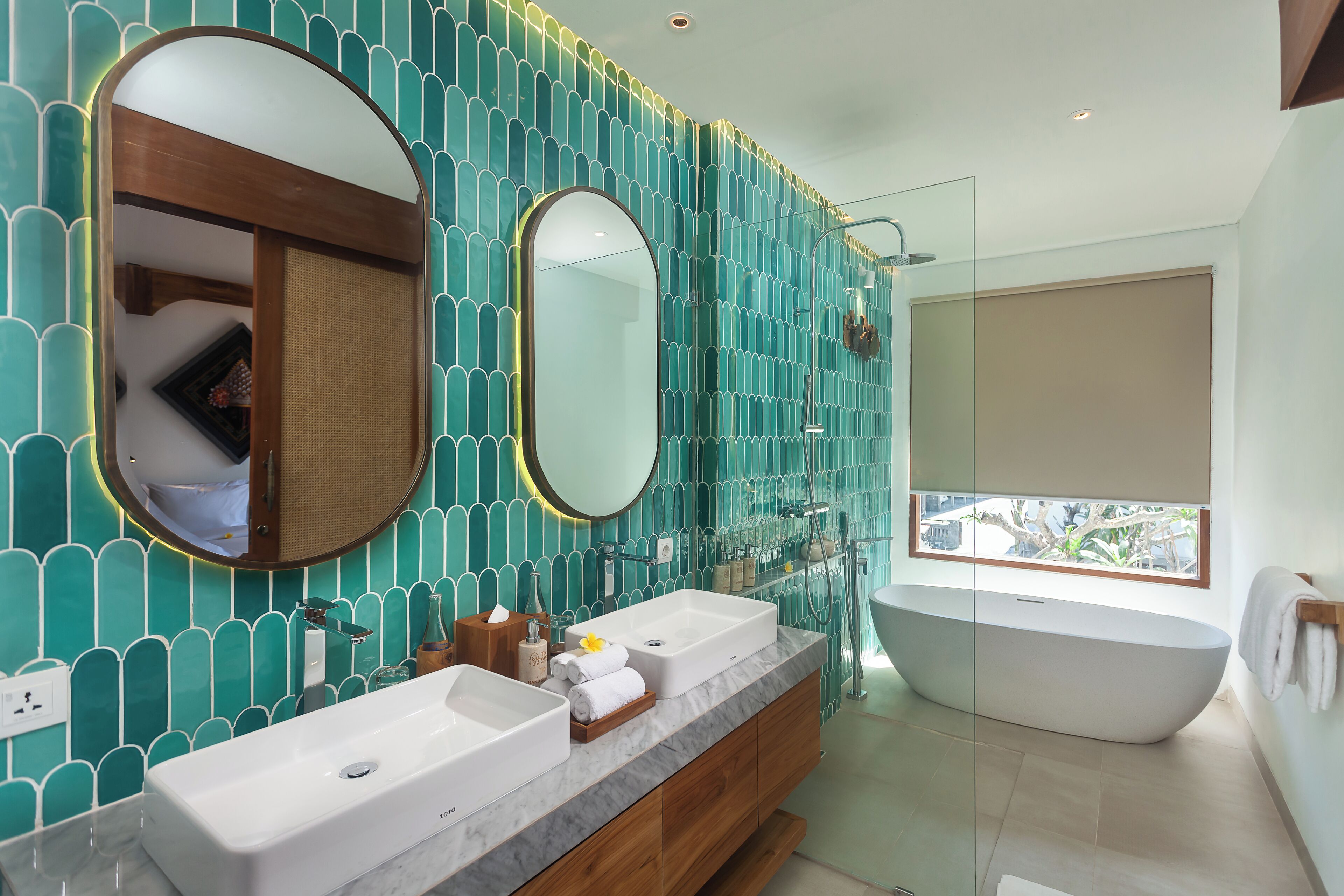 A modern bathroom with two sinks, a large mirror, and a freestanding bathtub.