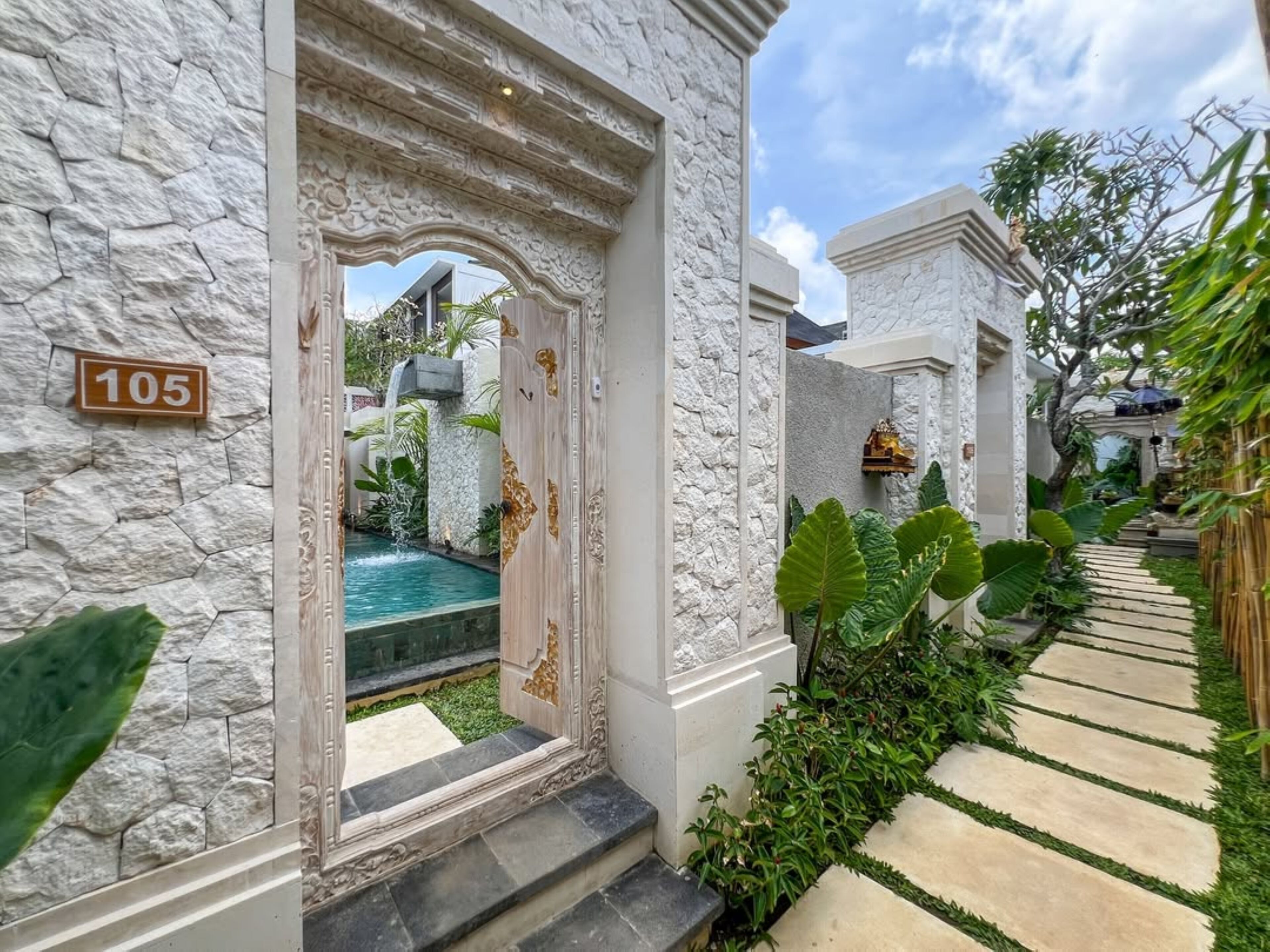 A stone building with a pool, a number sign '105', and a garden path.