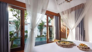 Un dormitorio con una cama grande, vistas a una piscina y cortinas ligeras.