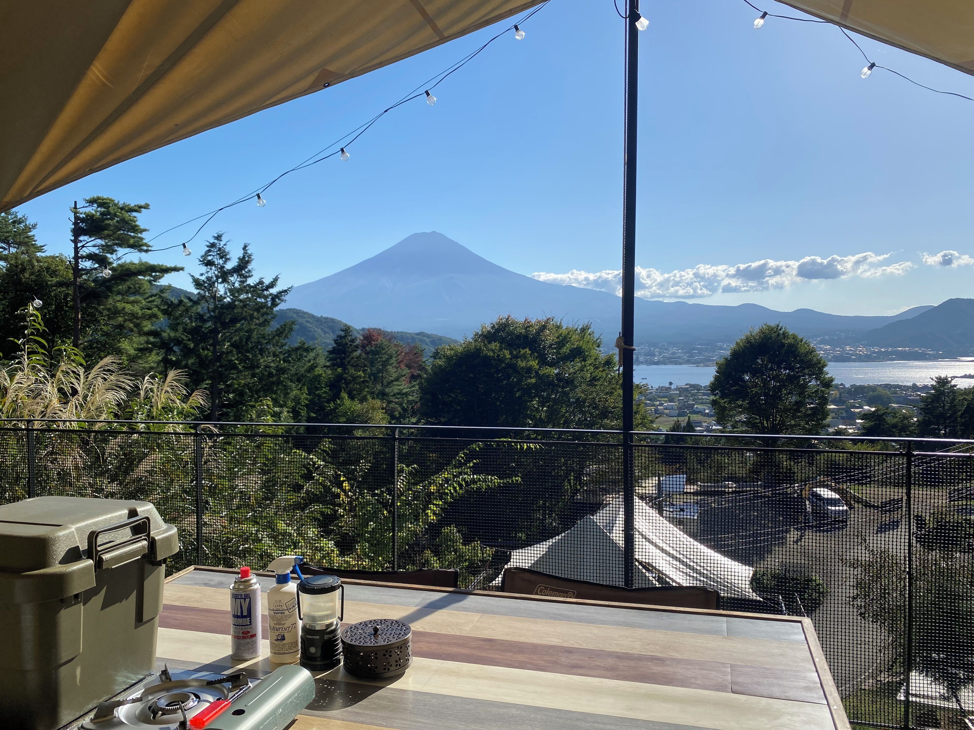 A balcony with a view of a volcano, a table with camping gear, and a netted railing.