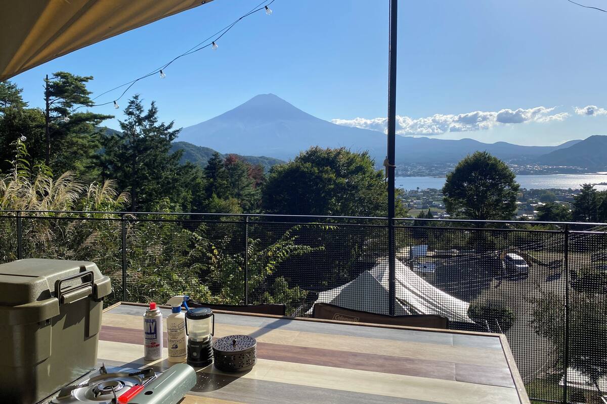 A balcony with a view of a volcano, a table with camping gear, and a netted railing.
