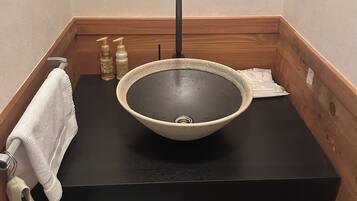 Un baño con encimera negra, lavabo de cesta trenzada y toallero.