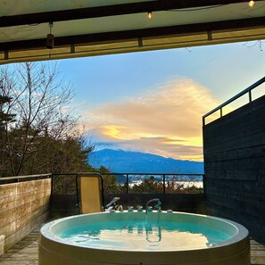 Un jacuzzi con vistas a una cadena montañosa y un atardecer.