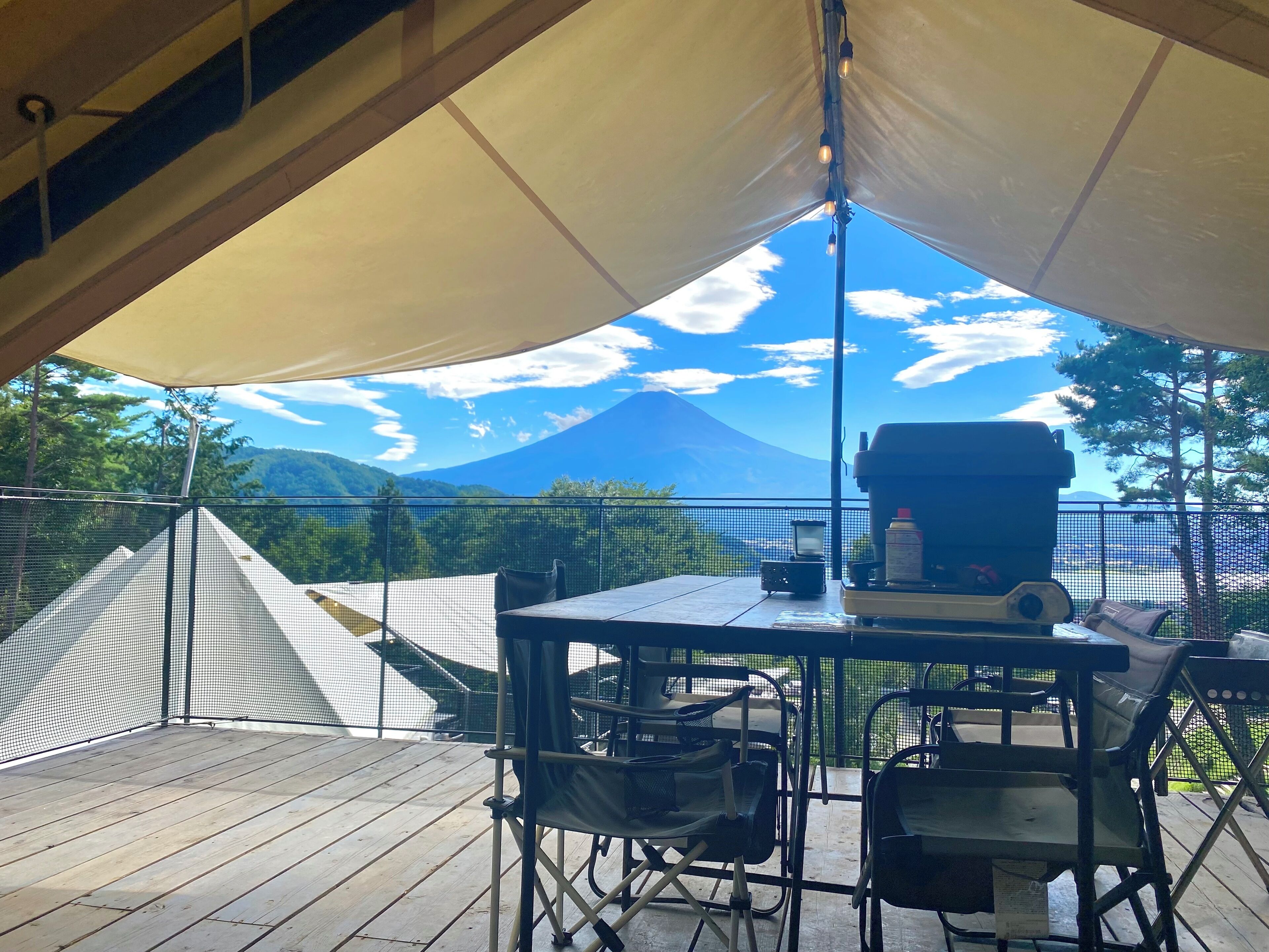 A tented outdoor area with a table, chairs, and a grill.