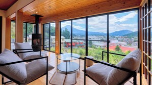 A spacious room with large windows, a fireplace, and comfortable seating. - Retreat Camp Mahoroba (Fujikawaguchiko)