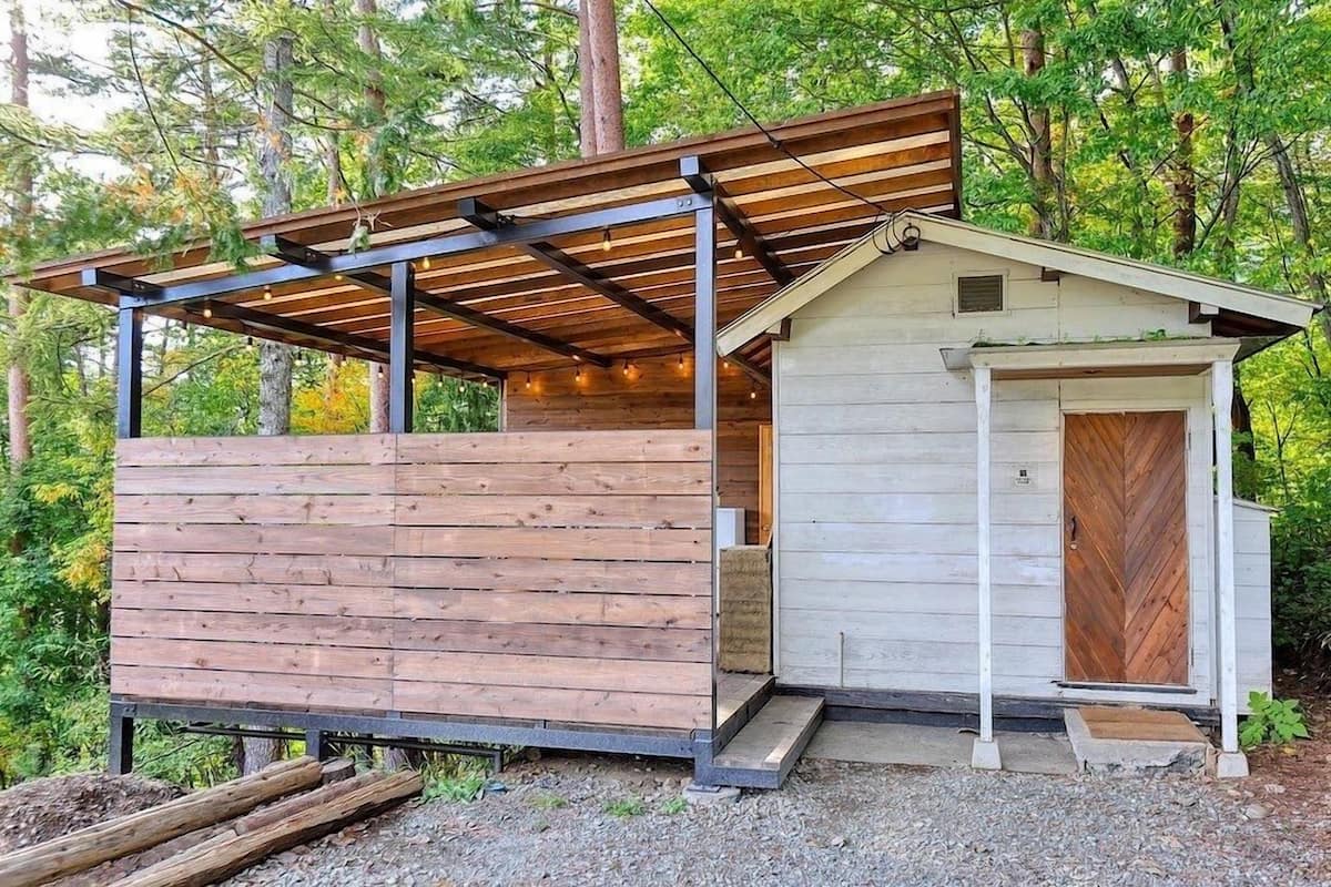 A small wooden cabin with a sloped roof and a porch area.