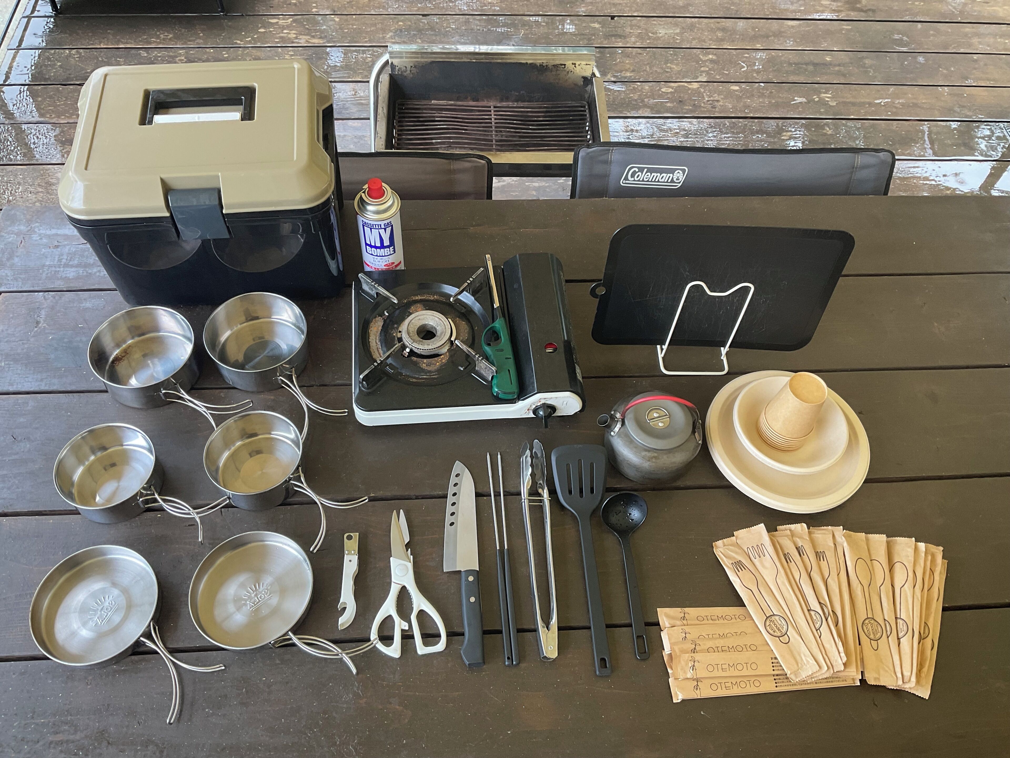 A camping setup with a Coleman stove, cooking utensils, and a portable gas canister.