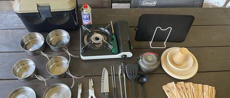 A camping setup with a Coleman stove, cooking utensils, and a portable gas canister.