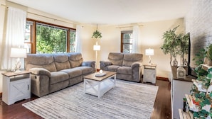 Una sala de estar con un sofá modular, dos sillones, una mesa de centro y una chimenea.