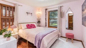 Un dormitorio con cama, mesita de noche, lámpara y ventana con cortinas.