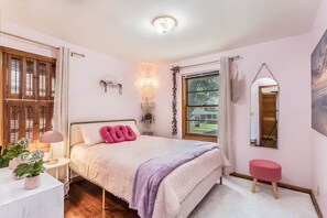 Una camera da letto con un letto, un comodino, una lampada e una finestra con tende.