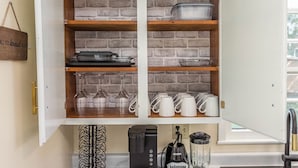 Una cocina con pared de ladrillo, estantes de madera y diverso menaje de cocina.