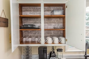Una cucina con parete in mattoni, mensole in legno e diversi utensili da cucina.