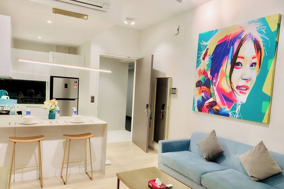 A modern living room with a light blue sofa, a coffee table, and a colorful painting on the wall.