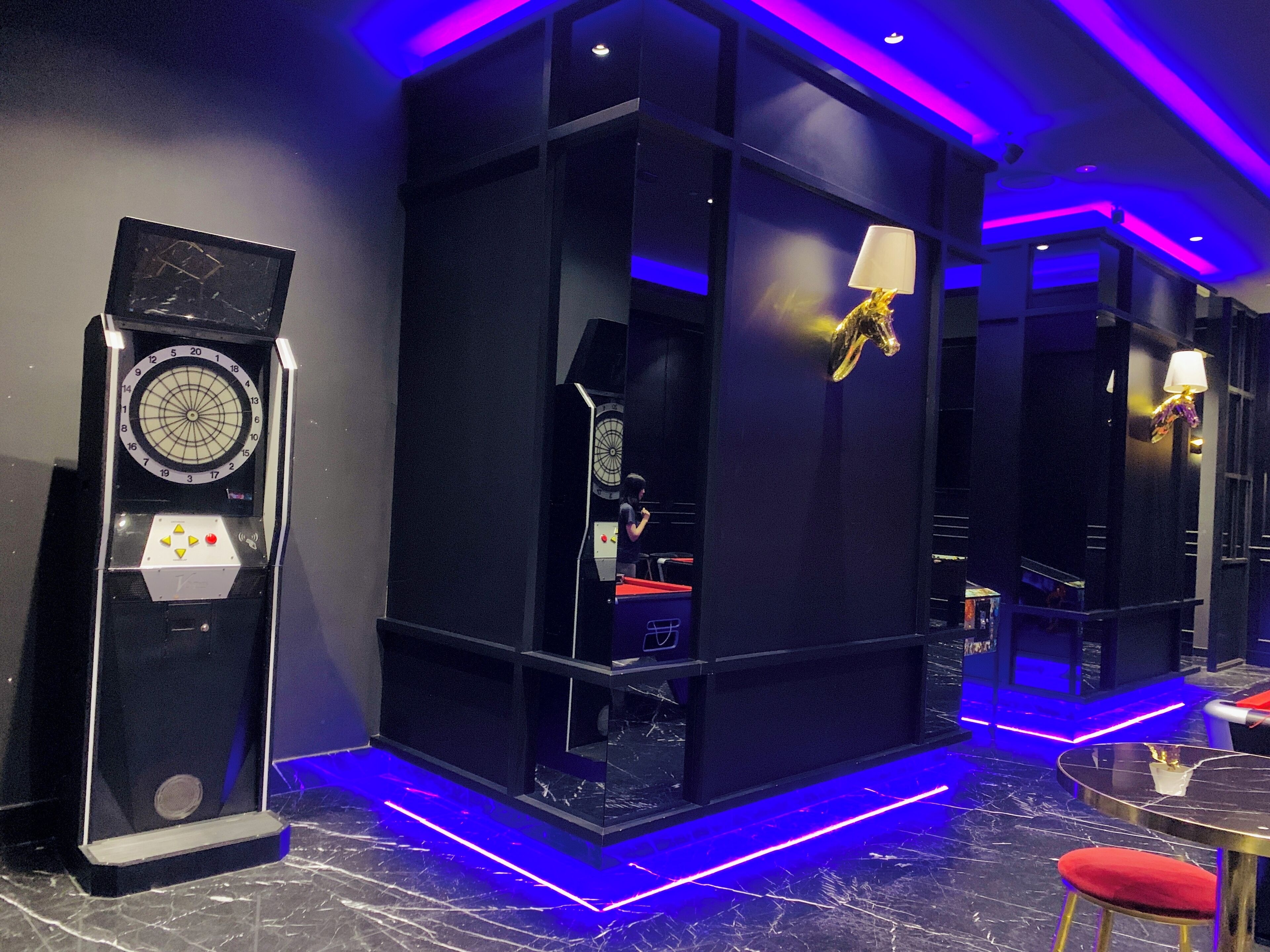 Una habitación moderna con un reloj grande, una lámpara original y un taburete acolchado rojo.