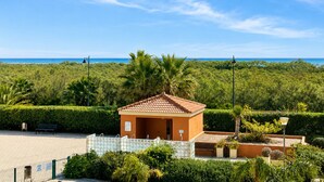A small building with a tiled roof, surrounded by lush greenery and a clear blue sky. - Los Pelícanos - Ref.412 (Punta del Moral)