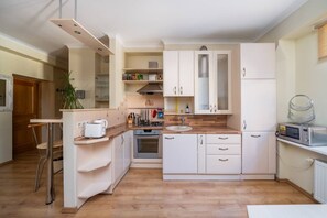A compact kitchen with white cabinets, a wooden countertop, a built-in oven, a sink, and a microwave. - Spacious and sunny apartment (Riga)