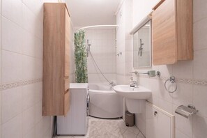 A compact bathroom with a bathtub, a sink, and a toilet. - Spacious and sunny apartment (Riga)