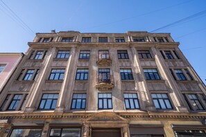 A multi-story building with a symmetrical facade, large windows, and a central balcony with ornate railings. - Spacious and sunny apartment (Riga)