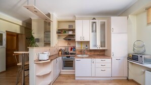 Une cuisine compacte avec des meubles blancs, un plan de travail en bois, un four encastré, un évier et un four à micro-ondes.