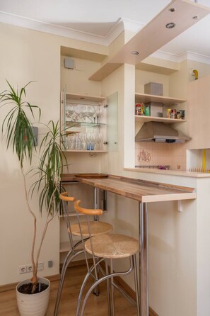 A modern kitchen with a built-in bar area, a potted plant, and a stool. - Spacious and sunny apartment (Riga)