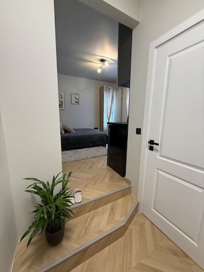 Cozy retreat with a neatly arranged bed, wall-mounted TV, and a touch of greenery.