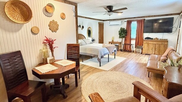 A spacious living area with a dining table, chairs, a sofa, and a TV.