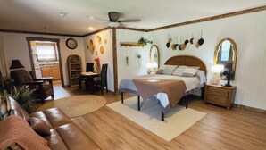A bedroom with a bed, bedside tables, a nightstand, a desk, a chair, and a sofa.