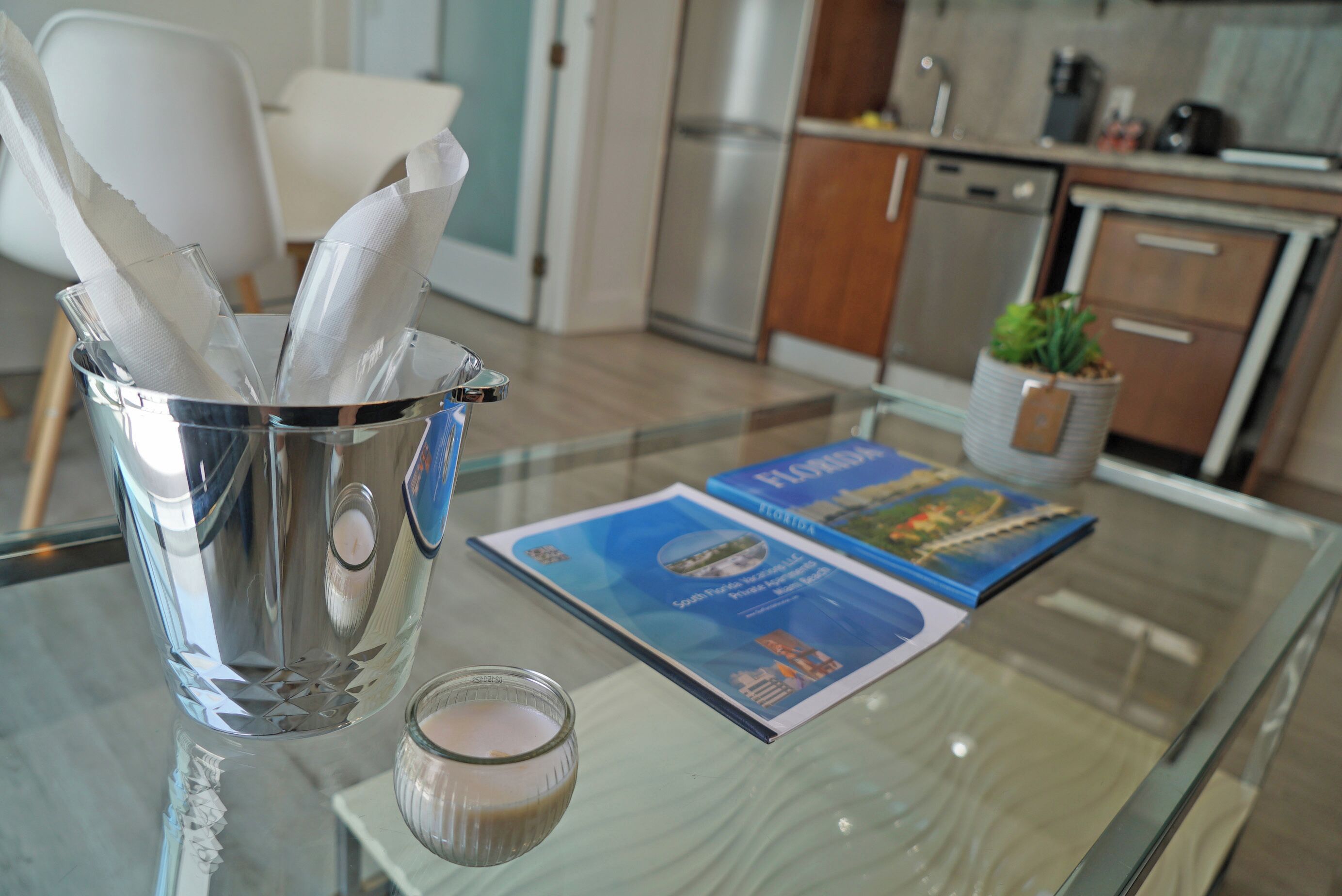 A glass table with a candle, a glass container with napkins, and a Florida travel brochure.