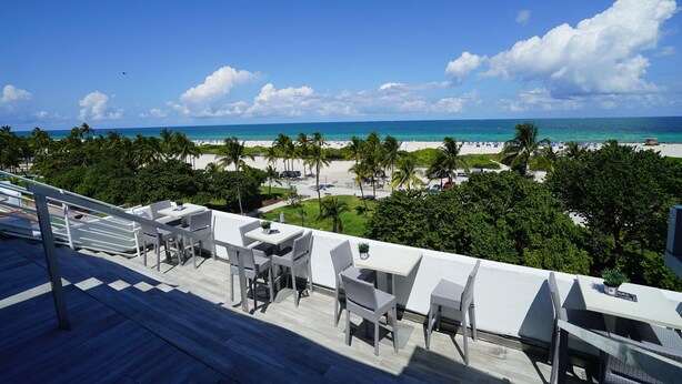 Une terrasse avec des sièges extérieurs donnant sur une plage et l’océan.