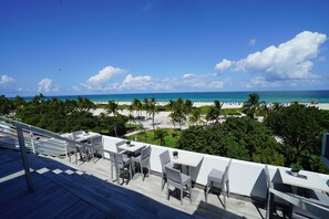 A terrace with outdoor seating overlooking a beach and ocean. - Private Apartment at the Congress  (Miami Beach)