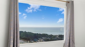 A window with a view of a coastal landscape, curtains, and a clear sky. - Charming 2BR Coastal Getaway in Pacifica (Pacifica)