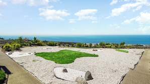 A landscaped garden with a pebble path, green grass areas, and a view of the ocean. - Charming 2BR Coastal Getaway in Pacifica (Pacifica)