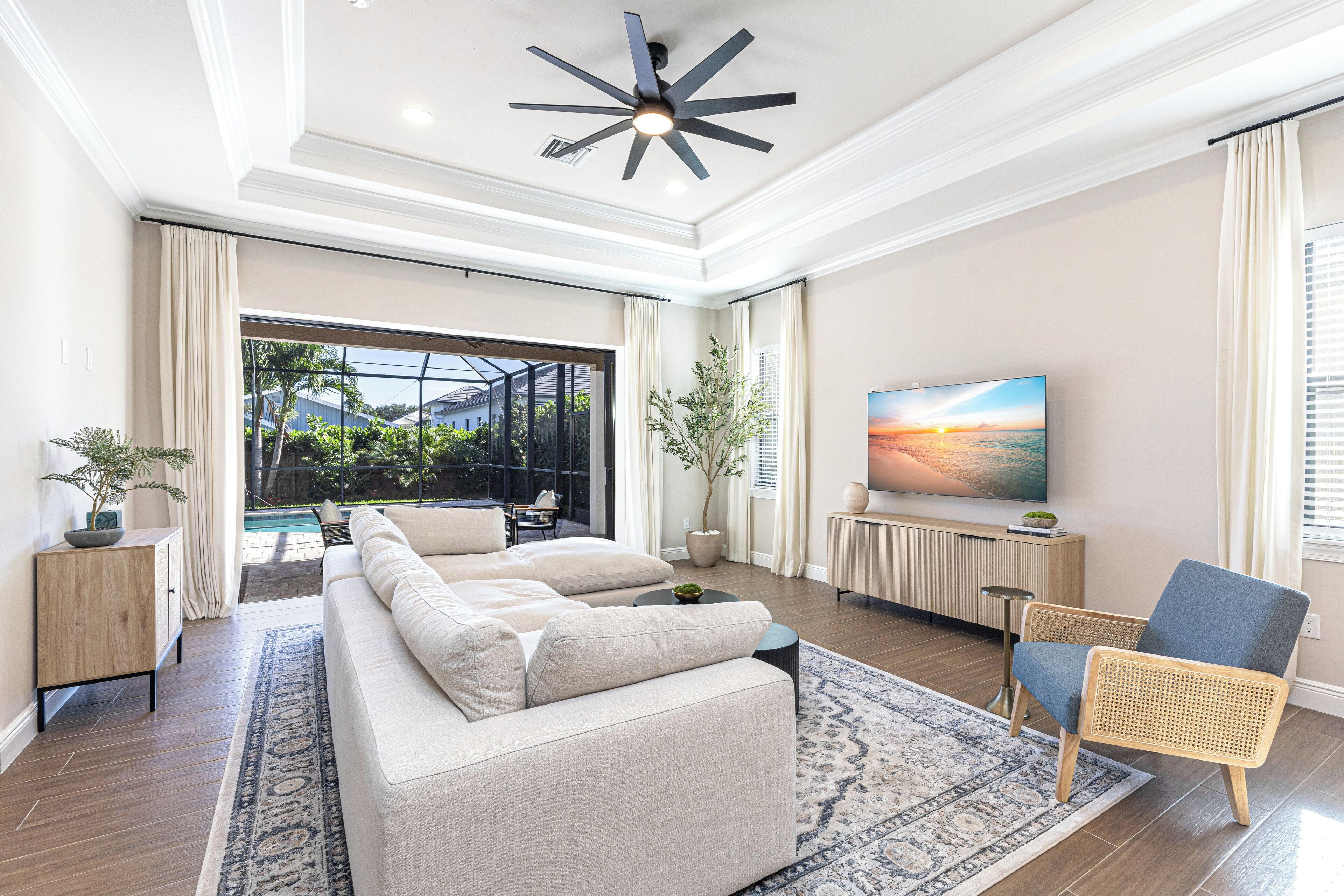 A modern living room with a large sofa, a dining area, and a TV on the wall.