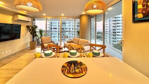 Een moderne woonkamer met een grote eettafel, comfortabele zitplaatsen en grote ramen met uitzicht op de stad.
