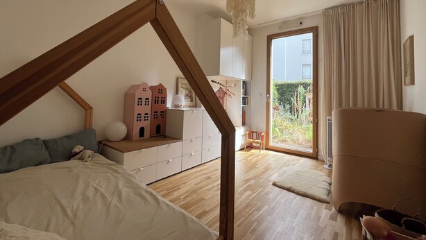 Un dormitorio con techo de madera, una cama, un aparador, una silla y vistas al exterior.