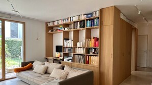 Una sala de estar moderna con un sofá, una estantería de madera y un escritorio con una computadora.