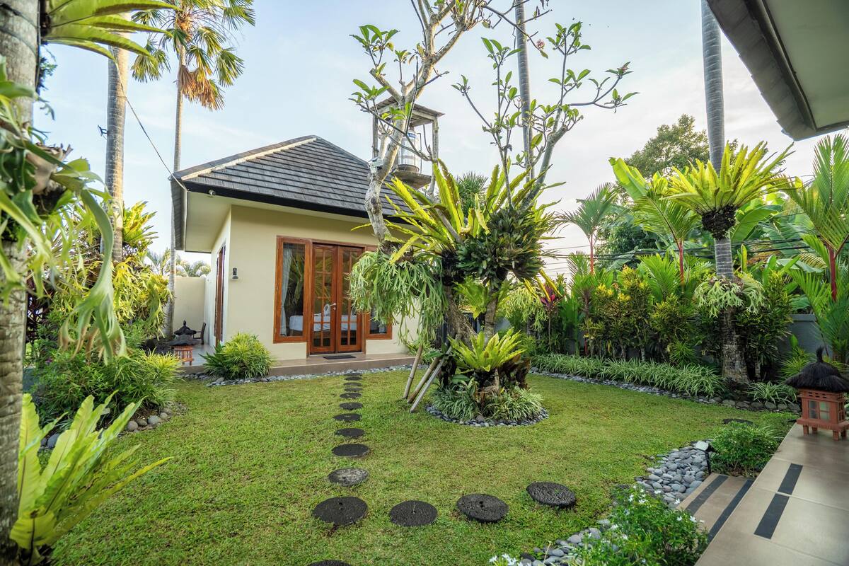 Una casa con un giardino curato, un vialetto in pietra e una struttura con tetto di paglia.