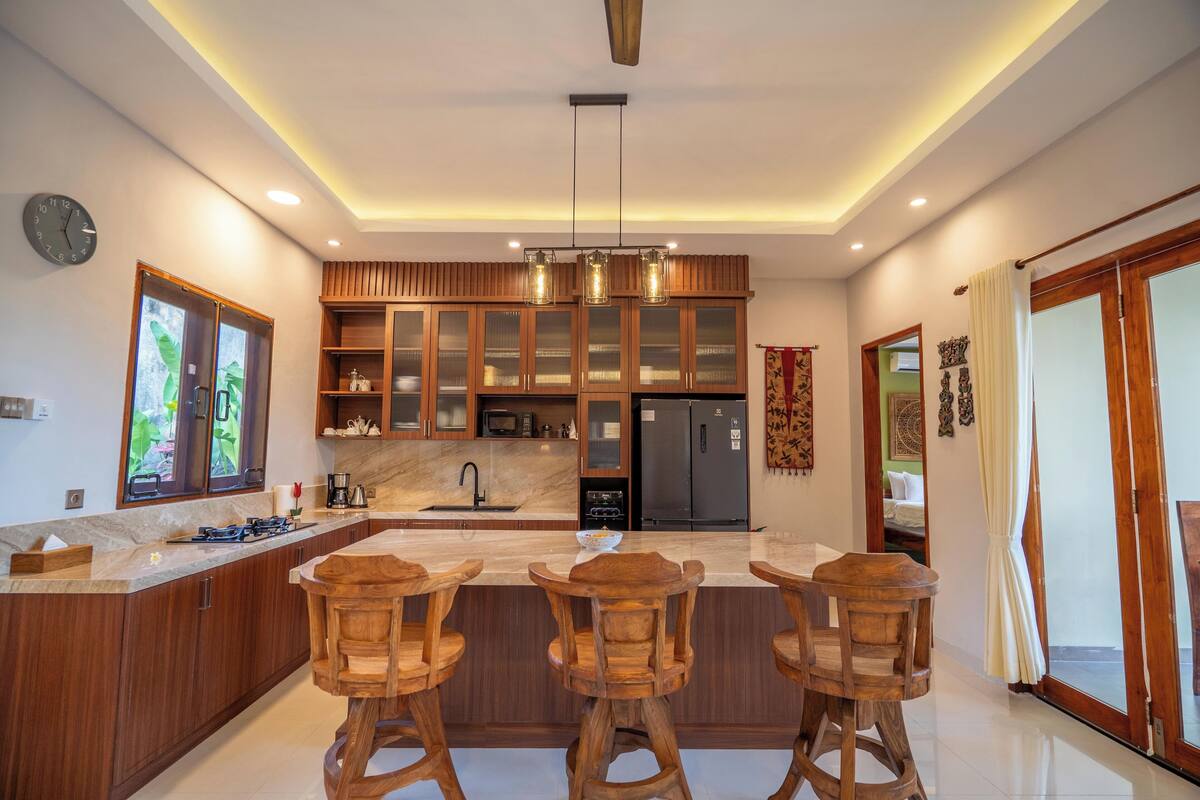 Una cucina moderna con mobili in legno, un piano di lavoro in marmo e un'isola centrale con sgabelli da bar.