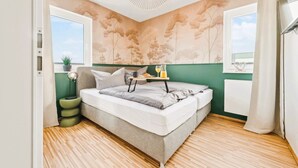 A bedroom with a bed, bedside table, and a window with curtains.