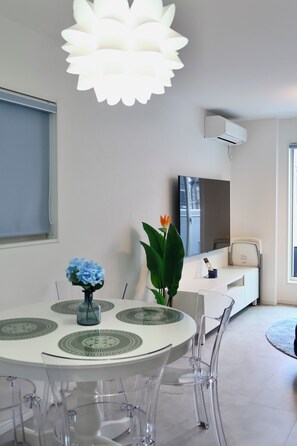 Un espace repas moderne avec une table ronde, des chaises transparentes et un luminaire décoratif.